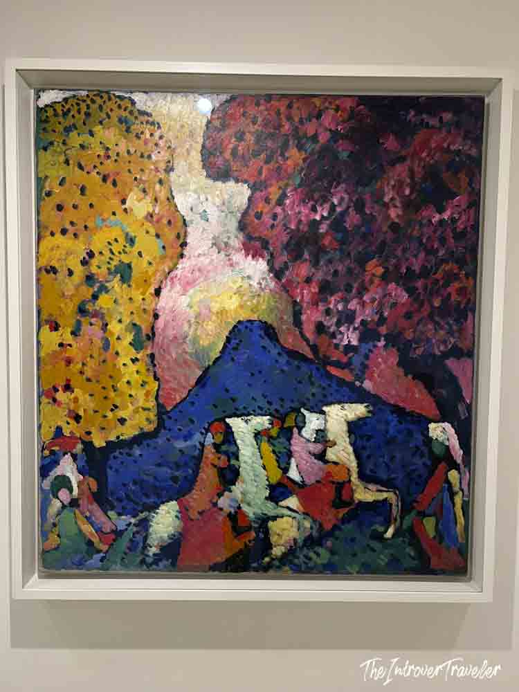 Kandinsky painting with bold colors, figures, and a blue mountain on display at the Guggenheim New York