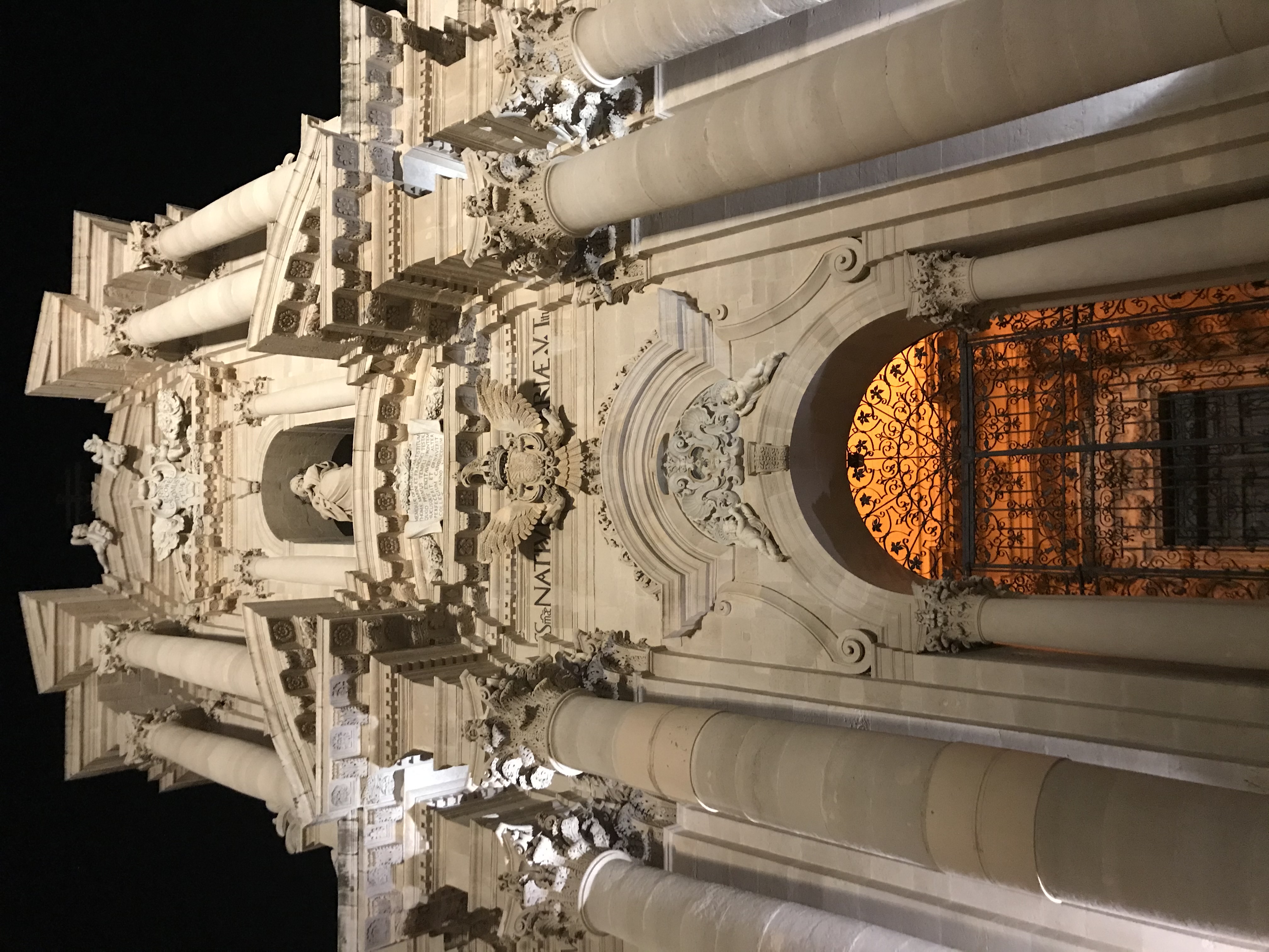 Ortigia Syracuse Cathedral baroque facade lit up at night with ornate carvings and glowing rose window