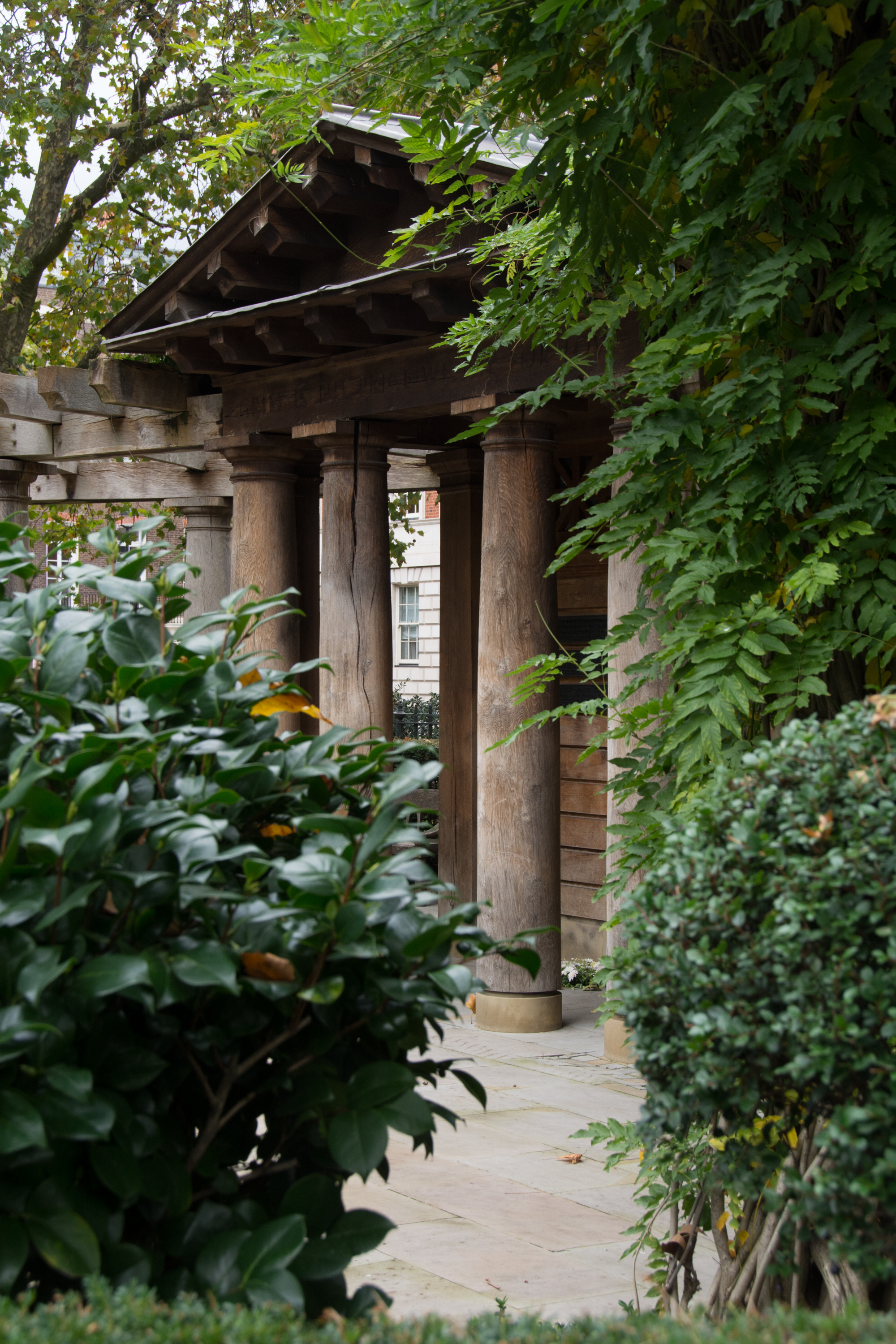 Stone columned pergola in the lush gardens near Trafalgar Square, London, framed by climbing greenery