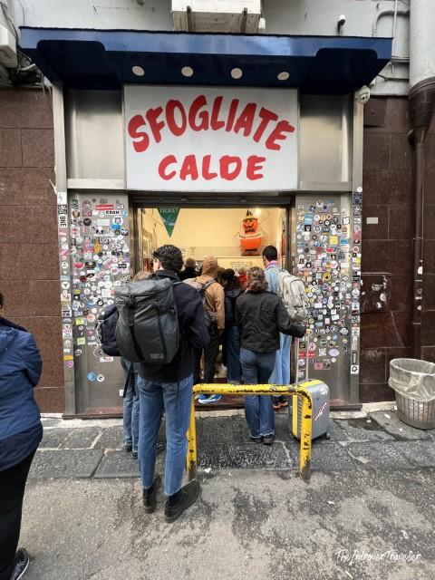 Crowd queuing at Sfogliatelle Attanasio storefront in Naples, covered in stickers