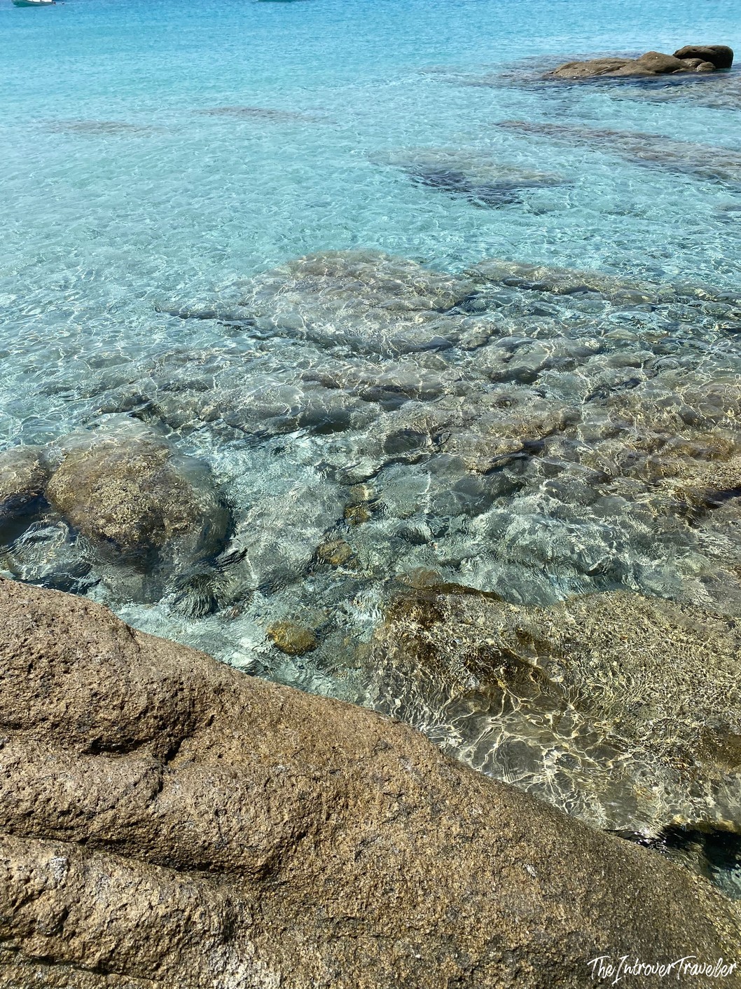 Crystal-clear turquoise water lapping over rocky seabed at a south Sardinia beach