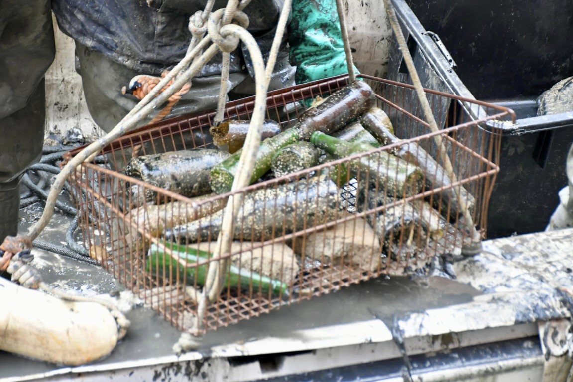 Mud-encrusted glass bottles retrieved from a Venice canal by divers during a cleanup dive
