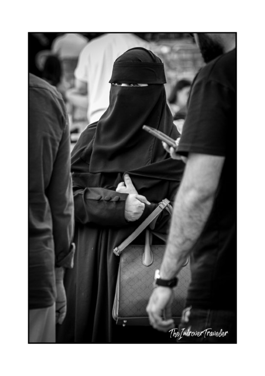 Woman in niqab and abaya carrying a handbag, candid street portrait in Istanbul