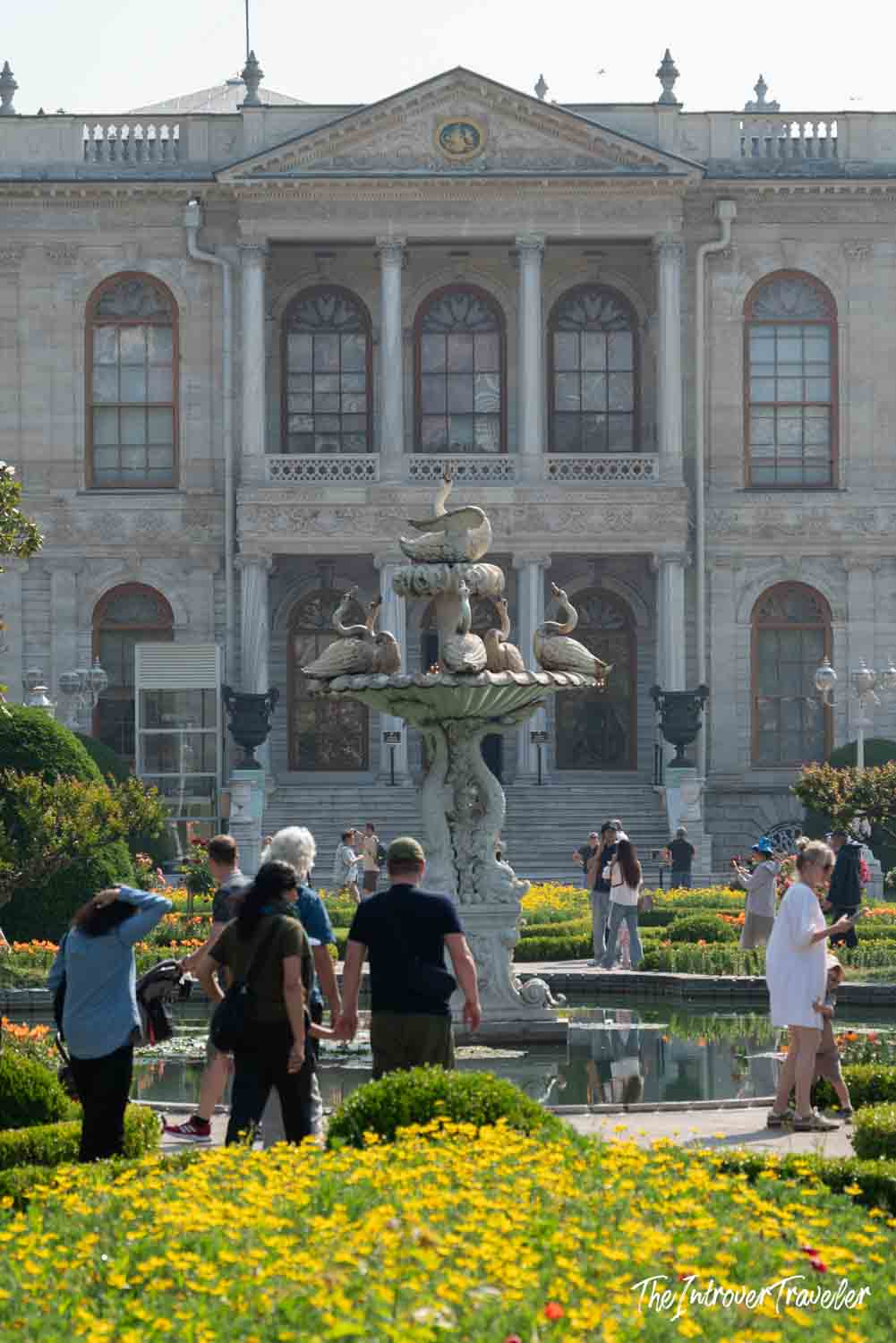 Dolmabahce Palace facade with swan fountain and blooming gardens, Istanbul visitors exploring the grounds