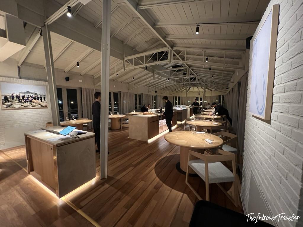 Elegant dining room interior of a fine dining seafood restaurant in Rimini, with wooden tables and vaulted ceiling