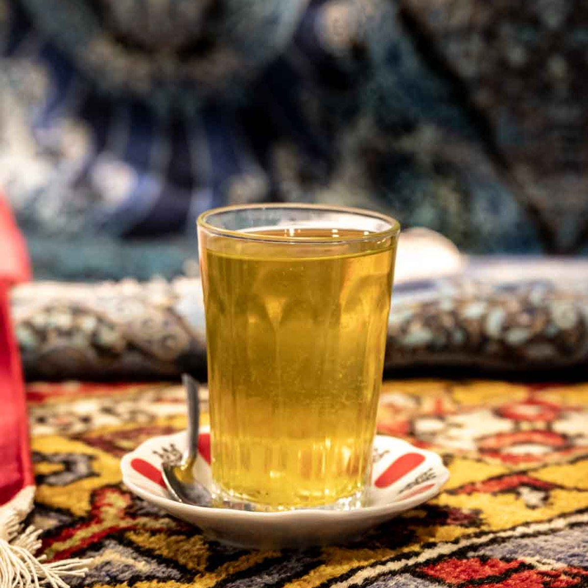 Glass of traditional Turkish herbal tea served on a saucer atop a patterned carpet in Istanbul