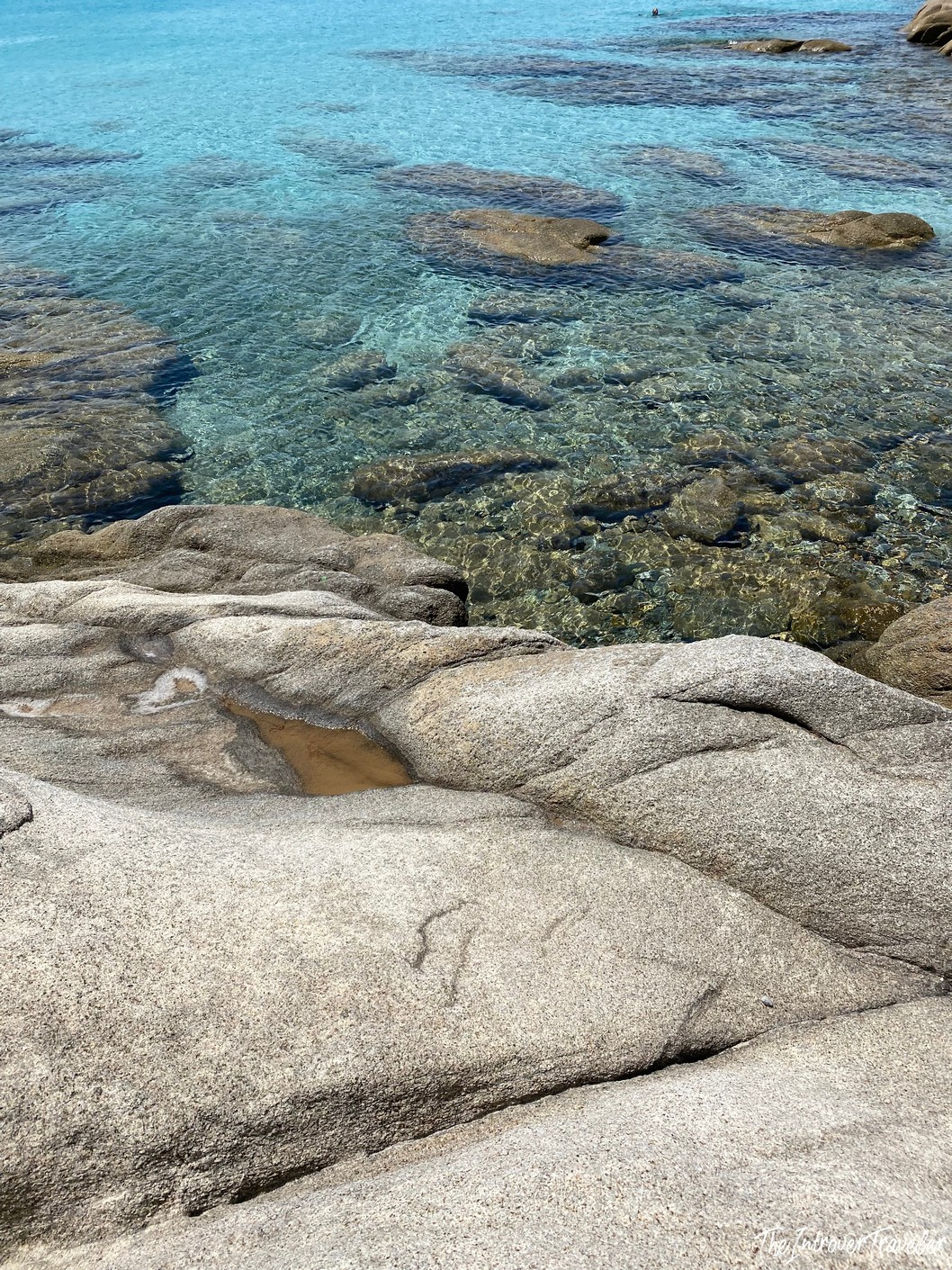 Smooth granite rocks meeting crystal-clear turquoise water at a south Sardinia beach cove