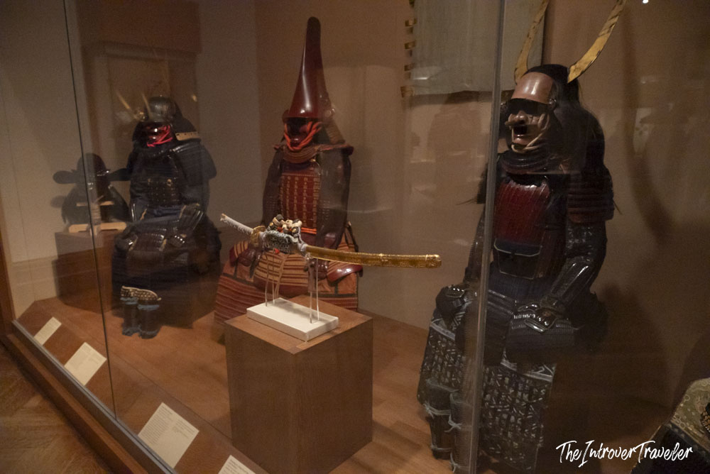Japanese samurai armor suits on display in a glass case at the Metropolitan Museum of Art