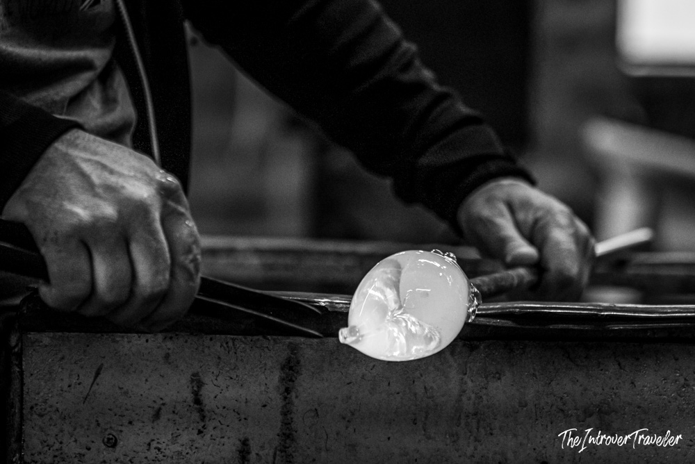 Murano glassmaker shaping a molten glass bubble on a blowpipe at a Venice furnace