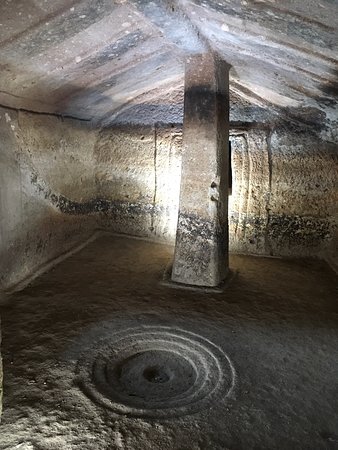 Interior of a Nuragic tomb near Mont'e Prama, Sardinia, with carved stone pillar and spiral floor motif