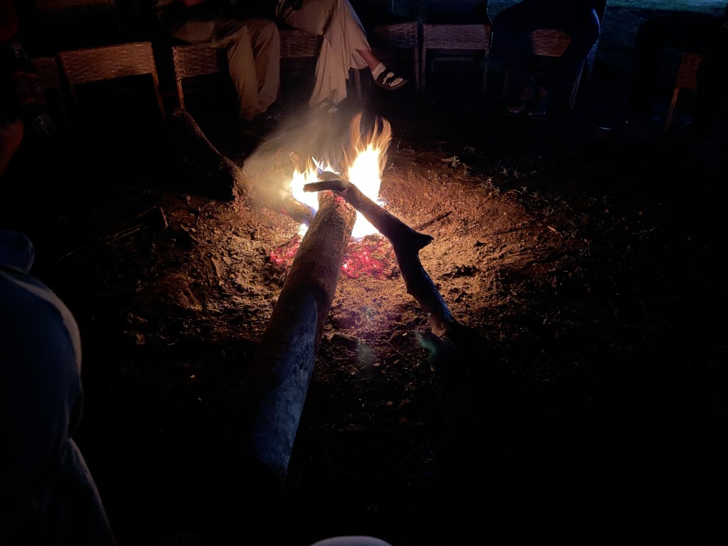 Guests gathered around a crackling campfire at night during a Tanzania safari lodge evening