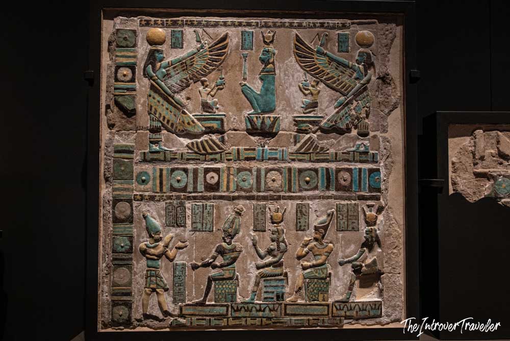 Colorful painted relief with winged deities and hieroglyphs on display at the Grand Egyptian Museum, Cairo