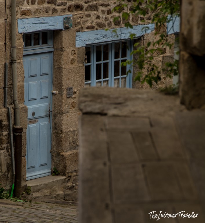 Historic granite house with pale blue door and shutters on a medieval street in Dinan, Brittany