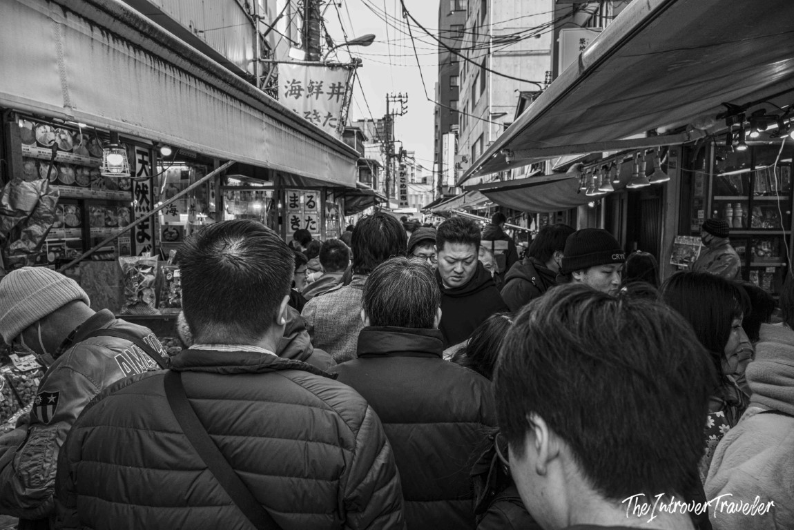 Crowded narrow alley at Tsukiji fish market Tokyo, packed with visitors between stalls and Japanese signs