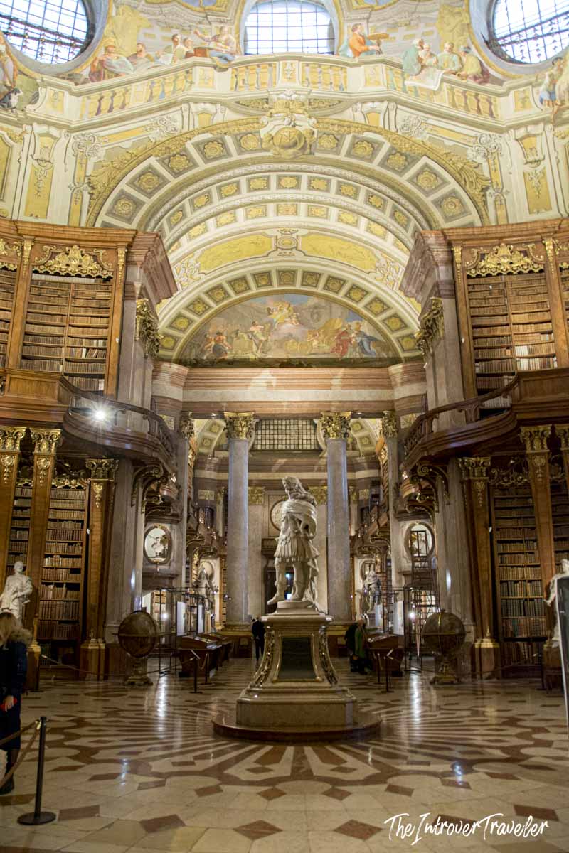 Austrian National Library State Hall in Vienna, baroque ceiling frescoes, statue of Charles VI, and towering bookshelves