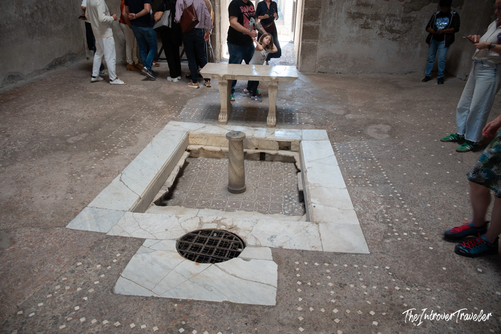 Marble impluvium and cartibulum in a Herculaneum atrium, surrounded by visiting tourists