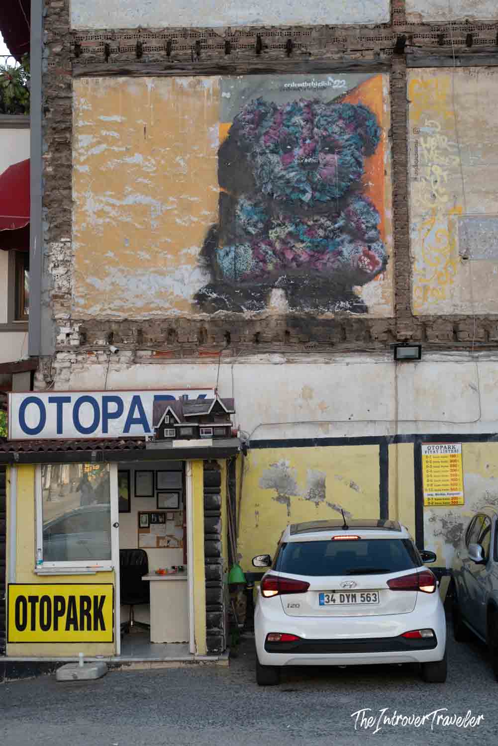 Street art mural of a dark textured teddy bear above an Otopark lot in Kadıköy, Istanbul