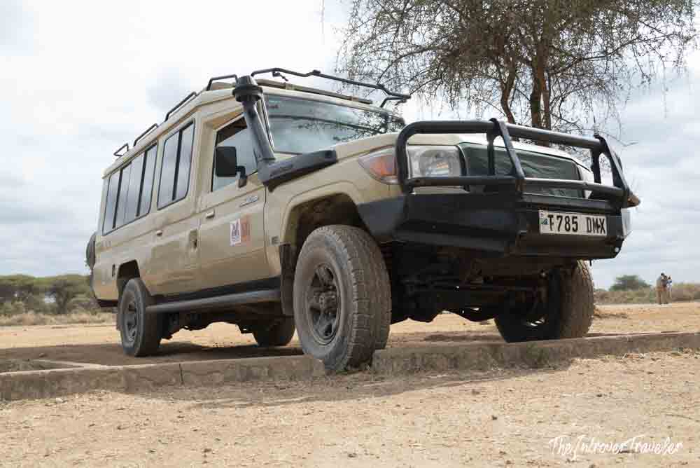 Tan Toyota Land Cruiser safari 4x4 parked on dry savanna terrain in Tanzania