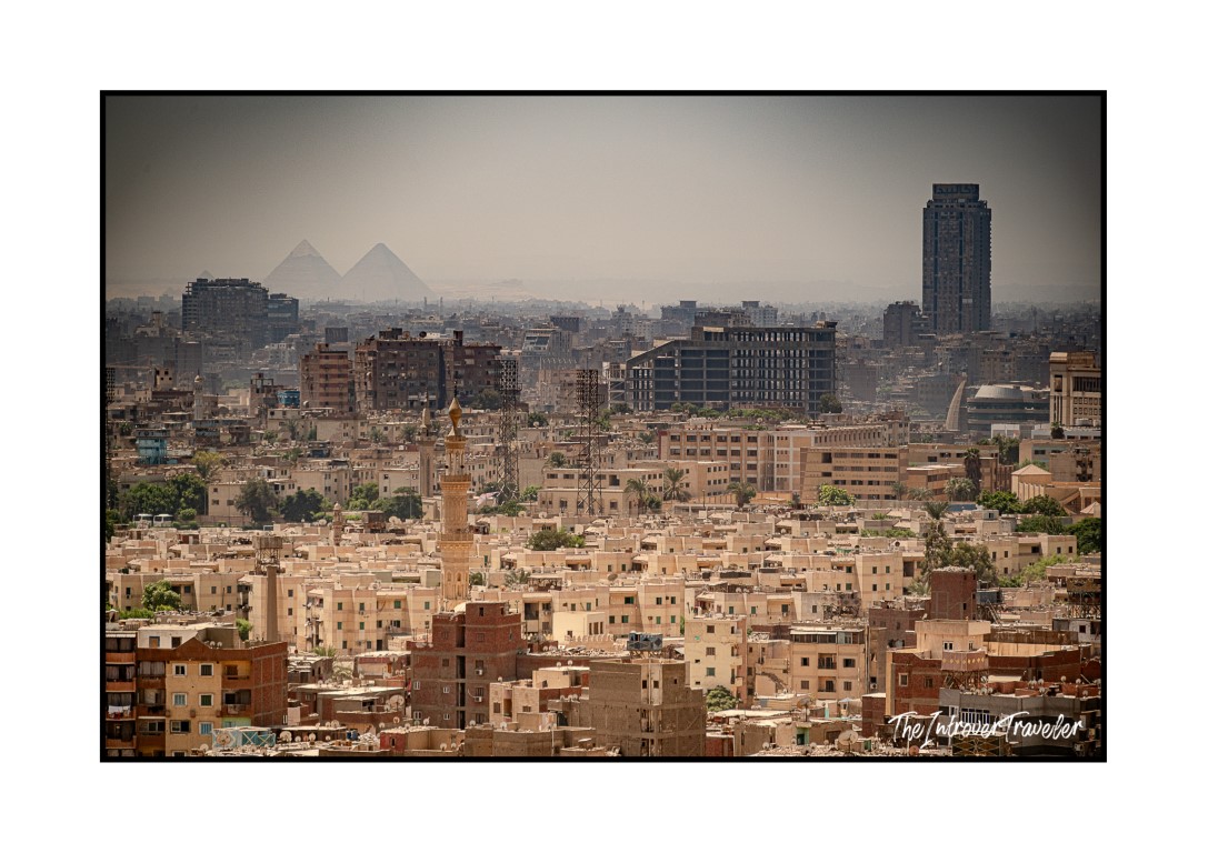 Cairo skyline with the Pyramids of Giza rising through the haze behind the dense urban sprawl