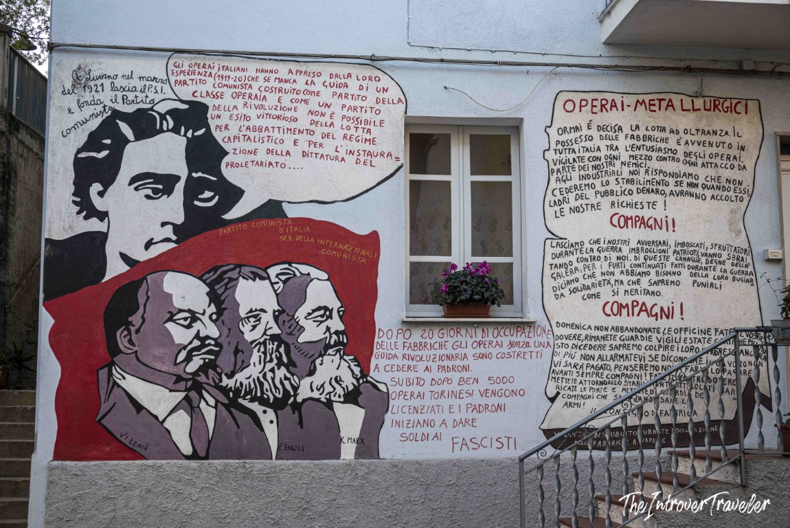Political mural in Orgosolo depicting Lenin, Engels, and Marx with Italian communist text on a building wall