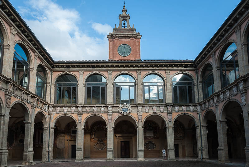 Archiginnasio Palace courtyard in Bologna, with arched arcades, clock tower, and decorative stone facades