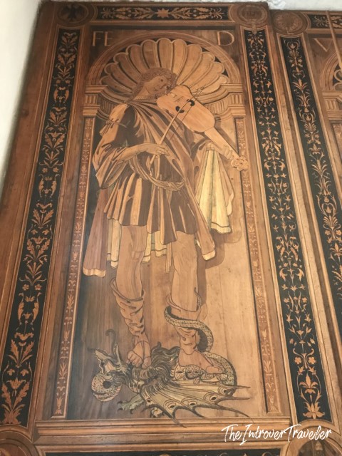Intarsia panel in the Studiolo of Federico da Montefeltro, showing a musician with violin over a dragon