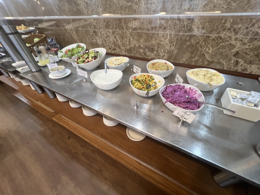 Salad bar at Turkish Airlines JFK lounge, featuring tzatziki, red cabbage, hummus, and corn salad bowls