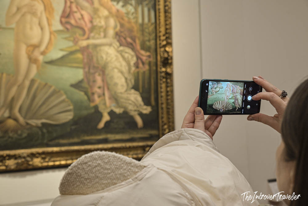 Visitor photographing Botticelli's Birth of Venus on a smartphone at the Uffizi Gallery, Florence