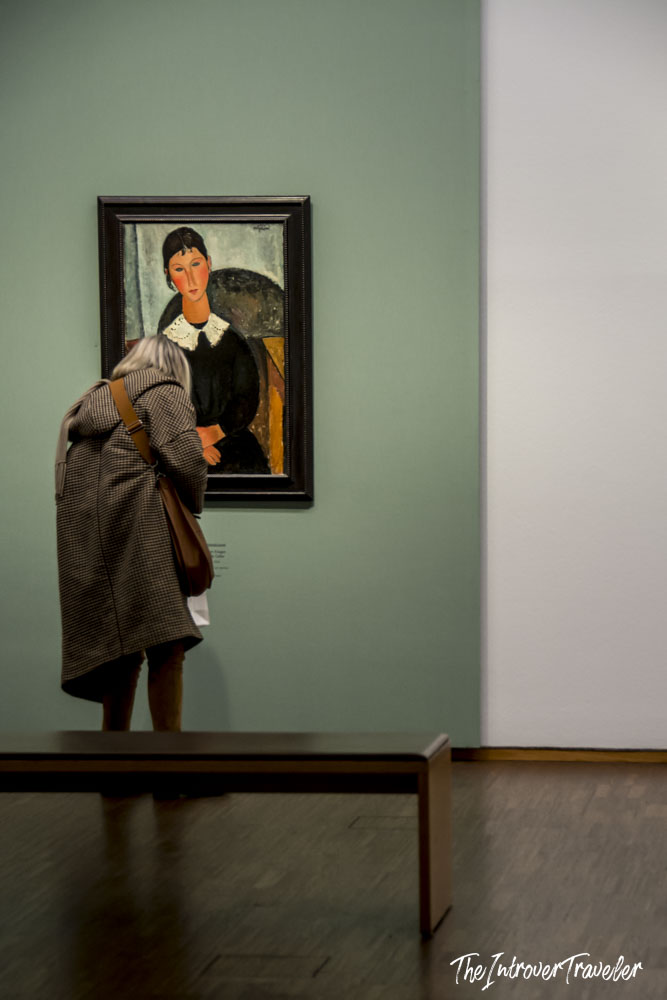 Visitor closely examining a Modigliani portrait at the Albertina Museum in Vienna
