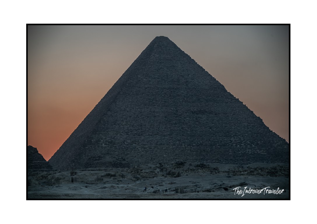 Great Pyramid of Giza silhouetted at dusk, showing its iconic steep inclination angle against a warm sunset sky.