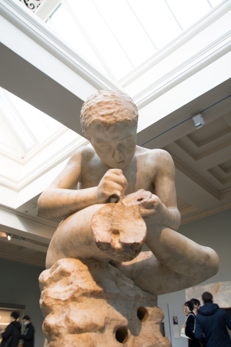 Ancient Greek marble boy sculpture displayed in the British Museum, London, under a skylit ceiling