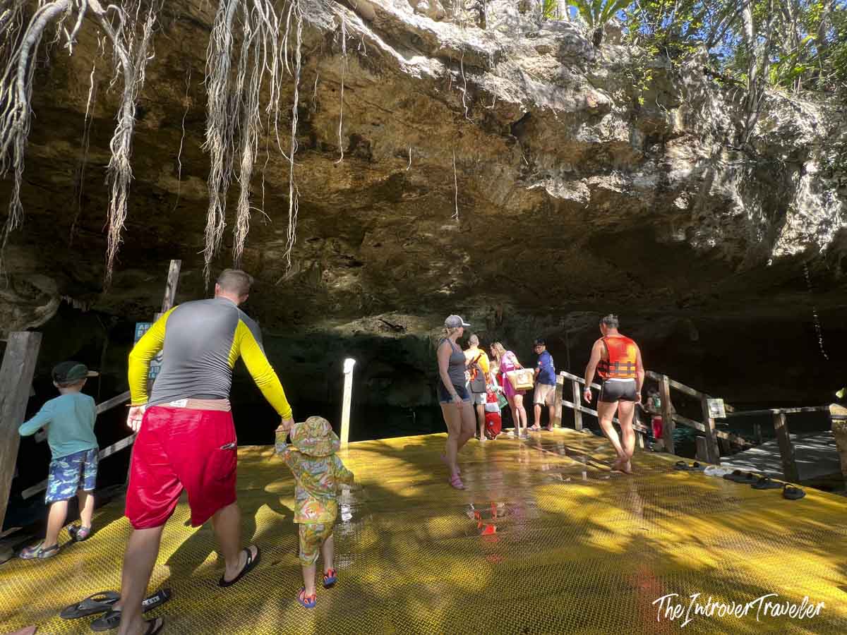 Tourists entering the cave opening of Dos Ojos cenote, Yucatan, on a yellow walkway platform