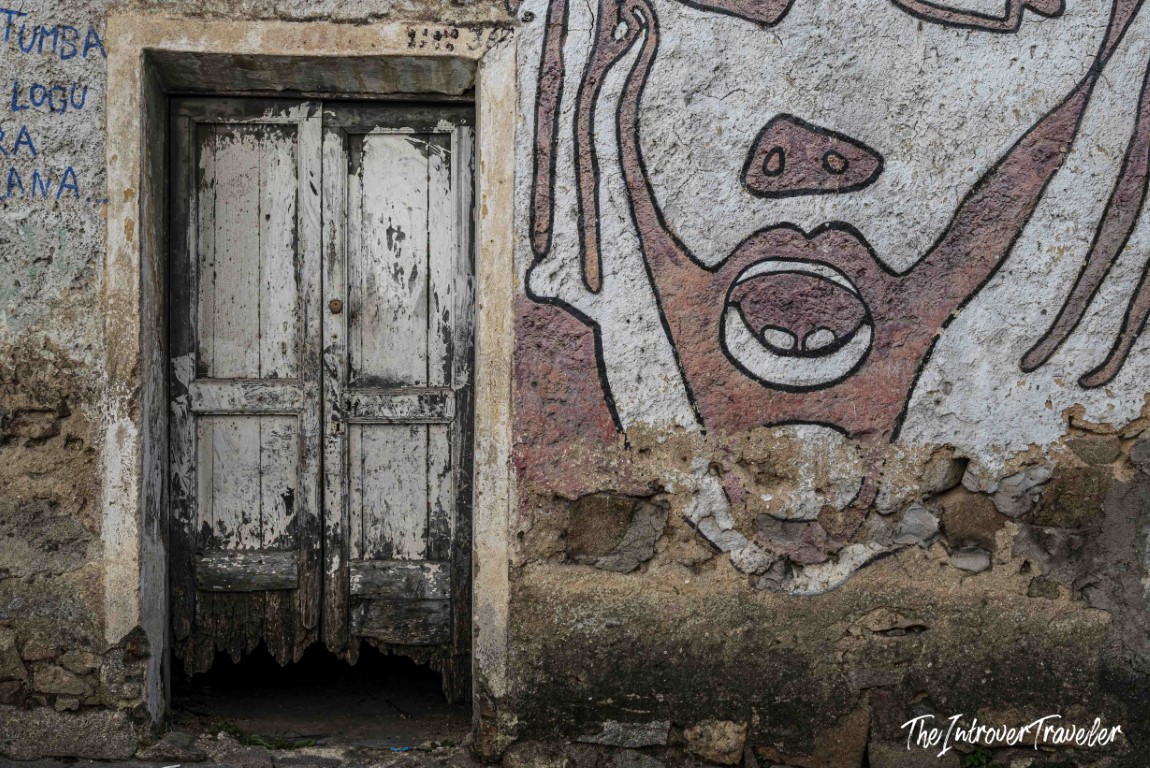 Weathered door beside a bold political mural on a crumbling wall in Orgosolo, Sardinia