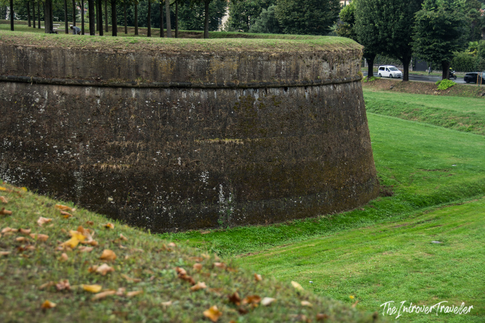 Massive stone bastion of Lucca's Renaissance city walls, lined with trees and green grass