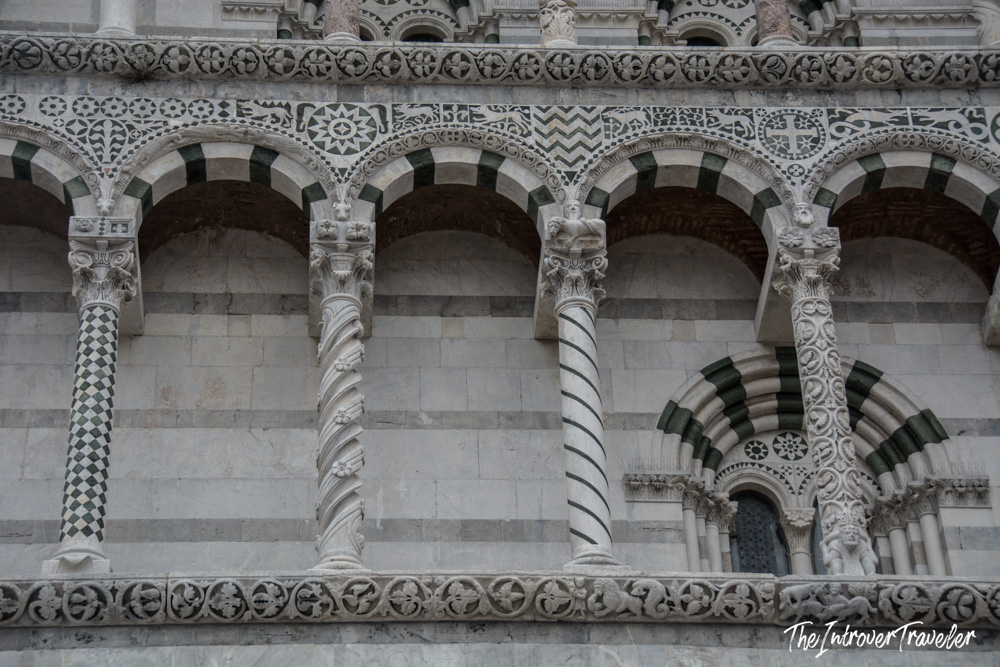 Ornate green and white marble columns and arches on the facade of Lucca Cathedral, Tuscany