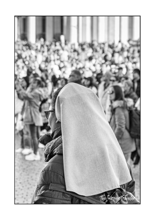 A nun with a white veil watches the crowd gathered for the Pope's Angelus in St. Peter's Square