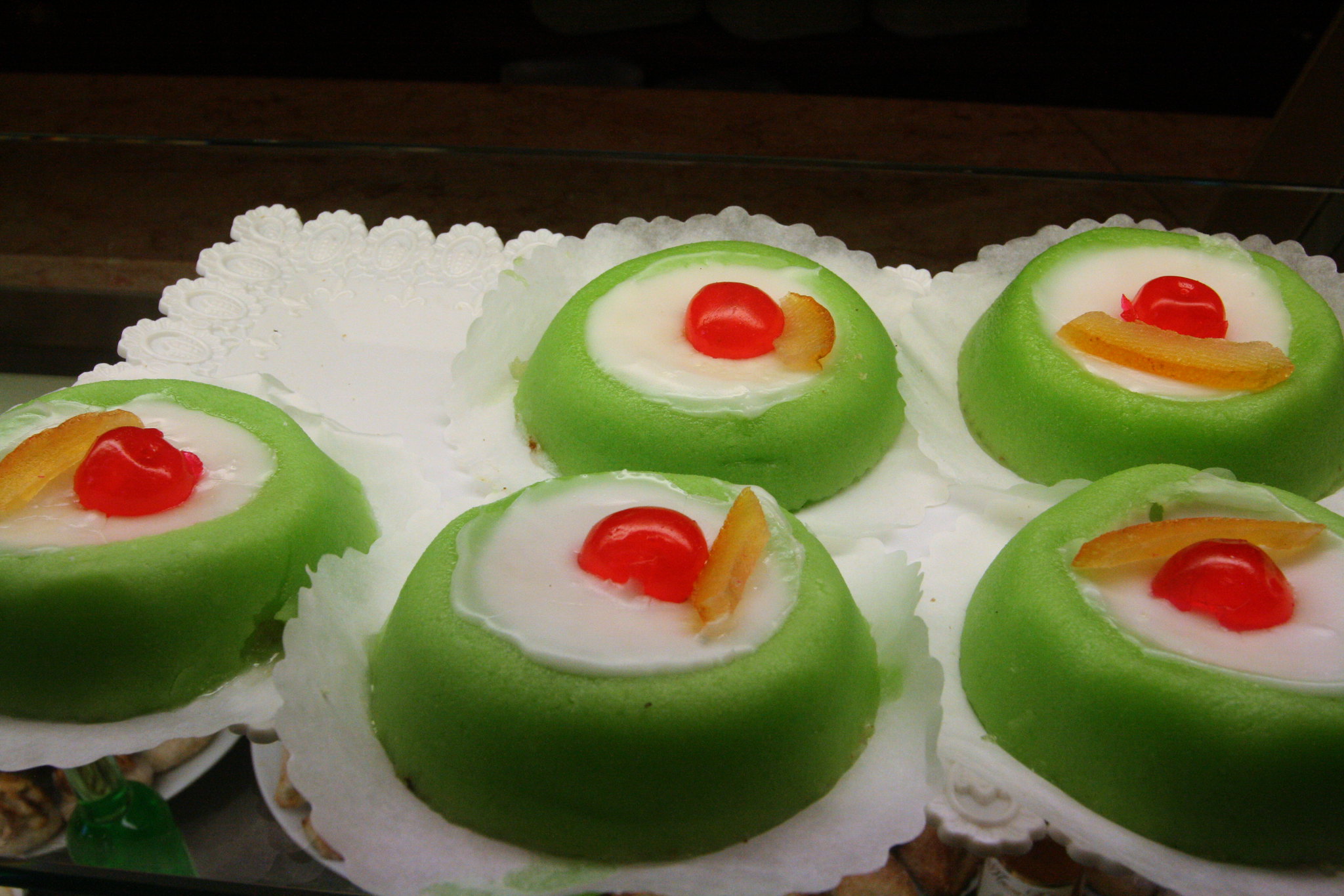 Cassatine siciliane with green marzipan, ricotta cream, candied fruit, and maraschino cherry topping