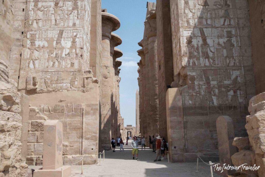 Visitors walking between towering hieroglyph-covered pylons at Karnak Temple Complex, Luxor, Egypt