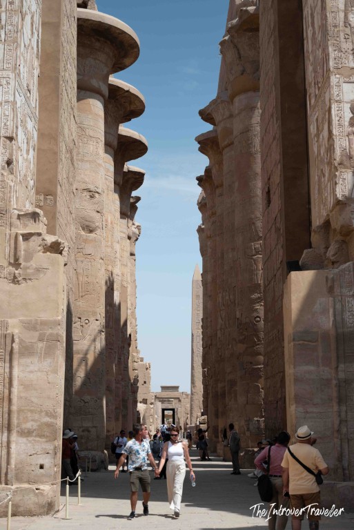 Tourists walking between massive papyrus columns in the Great Hypostyle Hall at Karnak Temple, Luxor