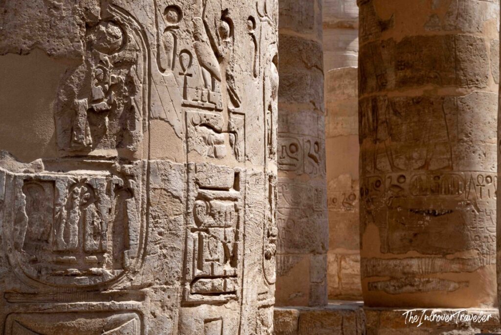 Hieroglyphic carvings and relief figures on sandstone columns at Karnak Temple Complex, Luxor