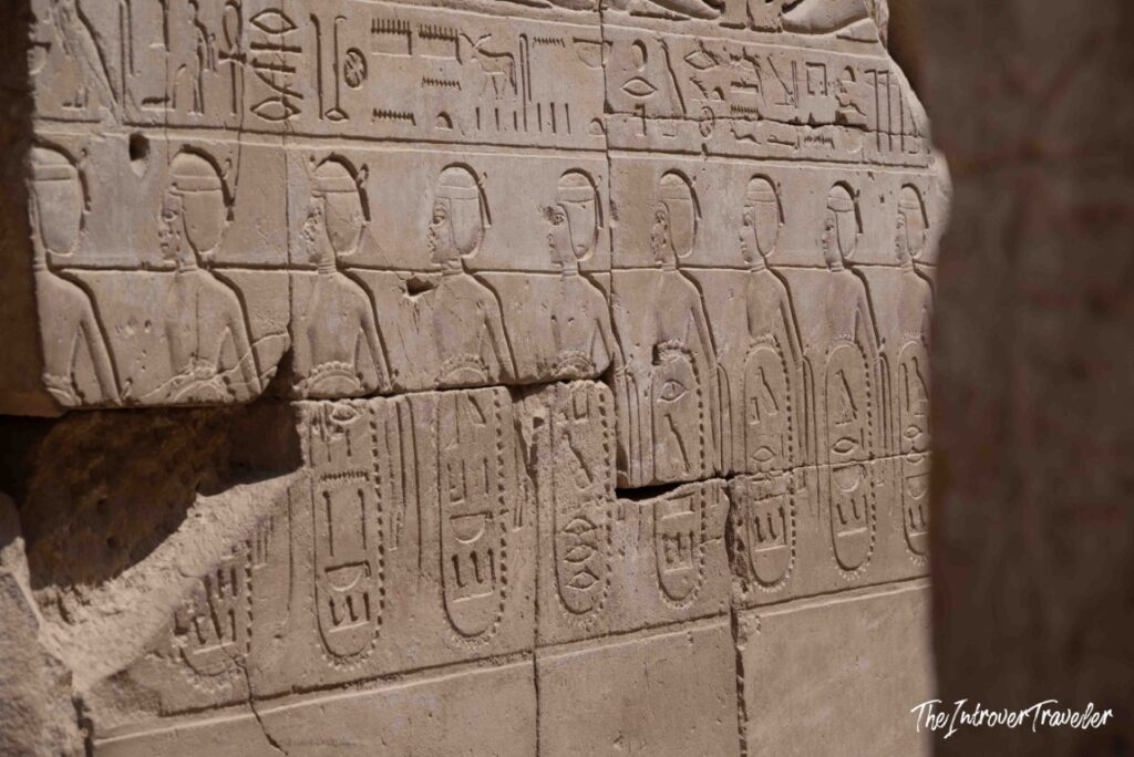 Ancient Egyptian hieroglyphs and carved figures on a stone wall at Karnak Temple Complex, Luxor