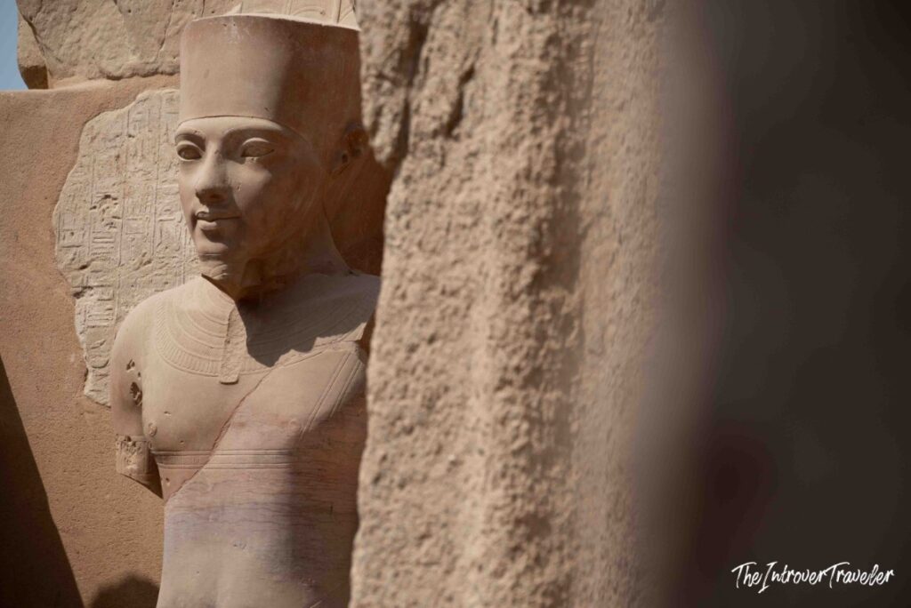 Colossal pharaoh statue framed between stone columns at Karnak Temple Complex, Luxor