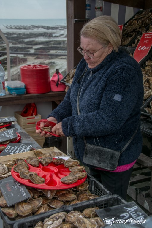 Vendor shucking fresh Cancale oysters at an outdoor market stall on the Brittany coast