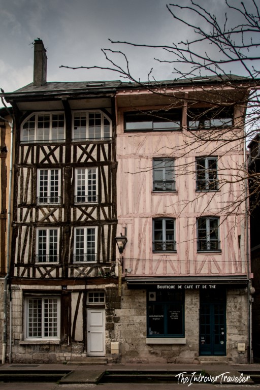 Half-timbered medieval buildings in Rouen, Normandy, with a pink facade and cafe boutique below