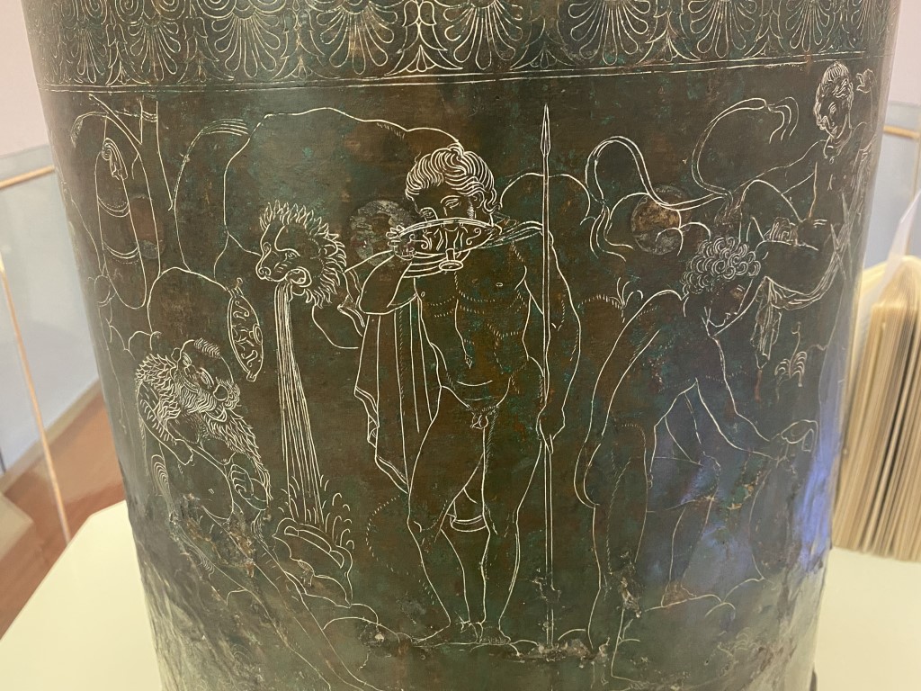 Close-up of silver-inlaid mythological engravings on an Etruscan bronze vessel at Villa Giulia, Rome