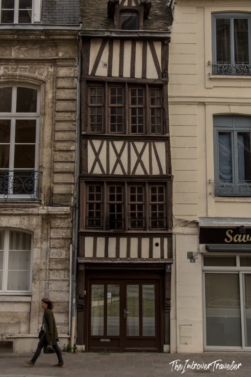 Narrow medieval half-timbered building on a Rouen street, squeezed between modern facades in Normandy