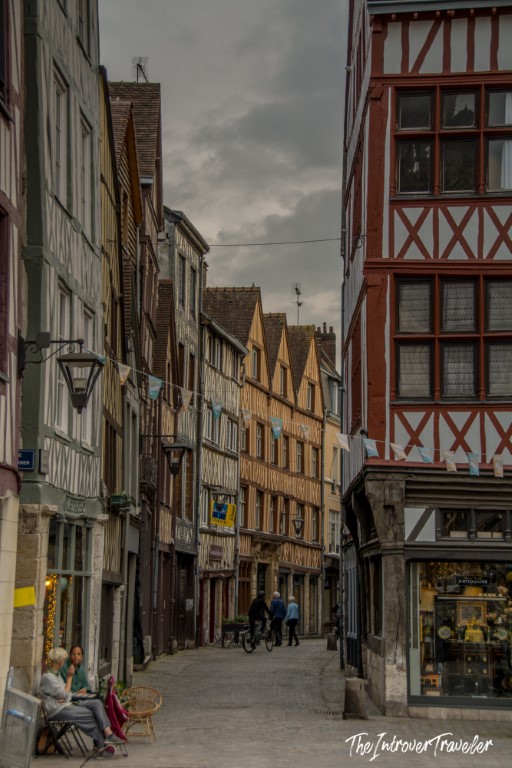 Narrow medieval street in Rouen lined with half-timbered Norman buildings under a cloudy sky