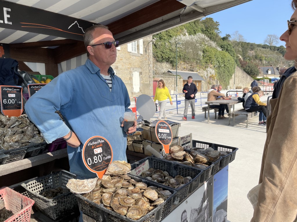 Cancale oyster vendor selling fresh huitres plates at a harborside market stall in Brittany