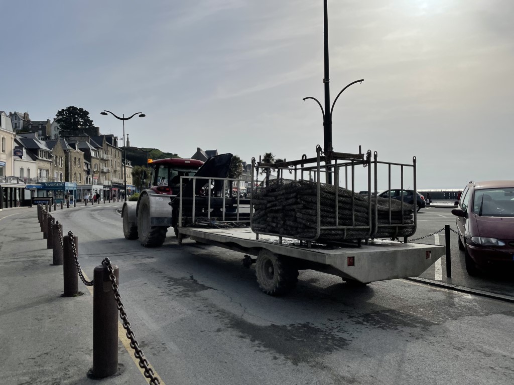 Tractor hauling oyster cages along the seafront promenade in Cancale, Brittany