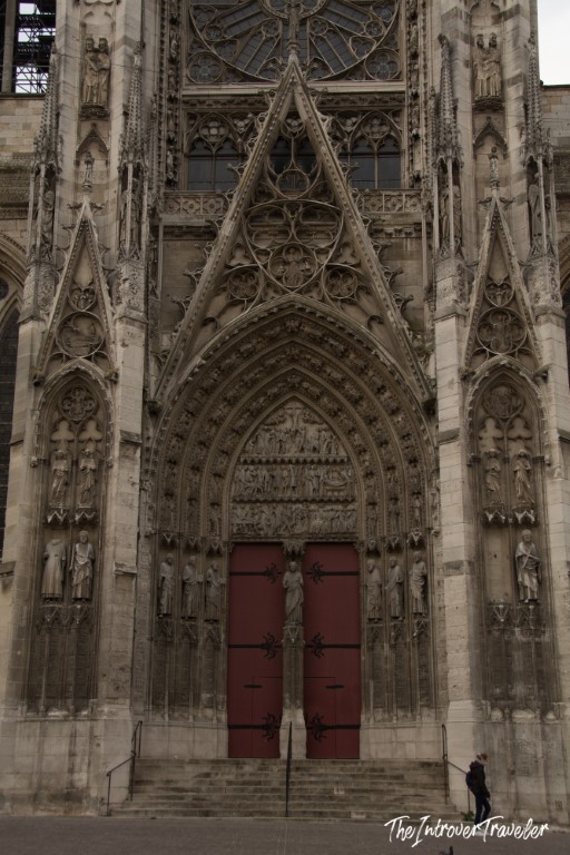 Gothic portal of Rouen Cathedral, with ornate stone carvings and red doors, Normandy France